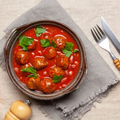 Meat or vegetable meatballs in tomato sauce with beans. Top view.