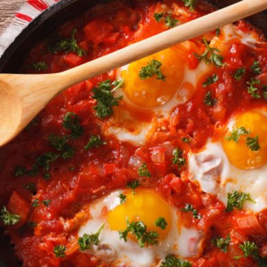 Shakshuka fried eggs macro in a frying pan. horizontal view from above