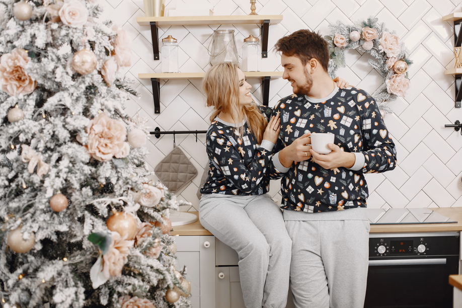 People in a Christman decorations. Man and woman in a identifical pajamas. Family in a kitchen.