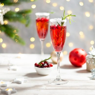Mimosa festive drink for Christmas - champagne red cocktail Mimosa with cranberry for Christmas party, copy space and fir tree branches