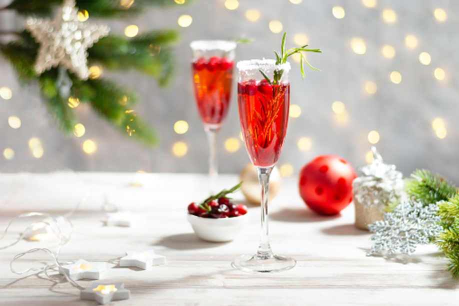 Mimosa festive drink for Christmas - champagne red cocktail Mimosa with cranberry for Christmas party, copy space and fir tree branches