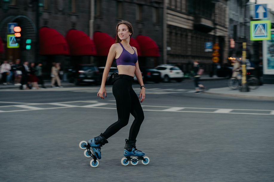 Full length shot of active slim young woman dressed in sportsclothes rides on rollers to strengthen arms and legs muscles improves balance agility and coordination has good mood burns calories