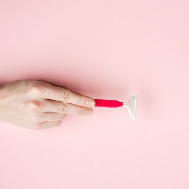 Woman hand holding razor blades. Isolated on pink background