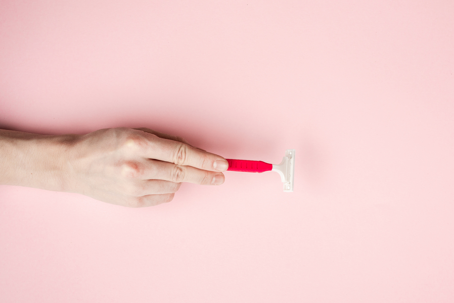 Woman hand holding razor blades. Isolated on pink background