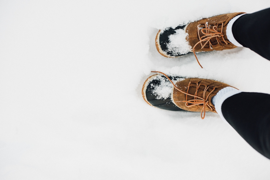 A high angle shot of warm fur boots covered with snow on the white ground