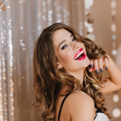 Wonderful young white lady with shiny dark hair posing with pleasure at christmas party. Lovable caucasian woman expressing happiness during photoshoot at event.