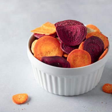Full bowl of veggie chips made from beets and carrots on a gray concrete background. vegan diet. horizontal image. space for text