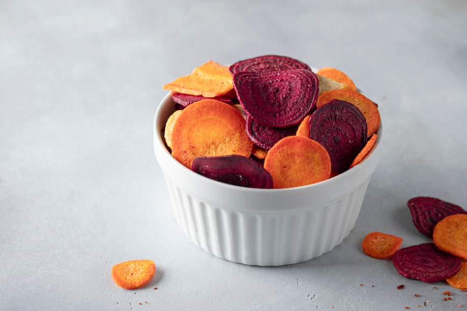 Full bowl of veggie chips made from beets and carrots on a gray concrete background. vegan diet. horizontal image. space for text