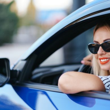 Confident and beautiful woman in sunglasses. Rear view of attractive young female in casual wear driving a car