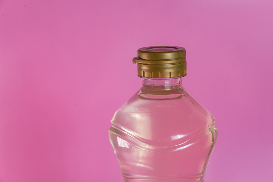 Container of vinegar on the pink background