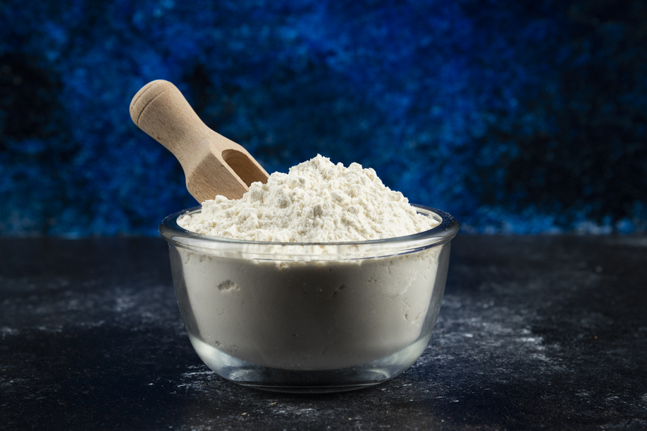 Glass bowl of flour on blue background. High quality photo