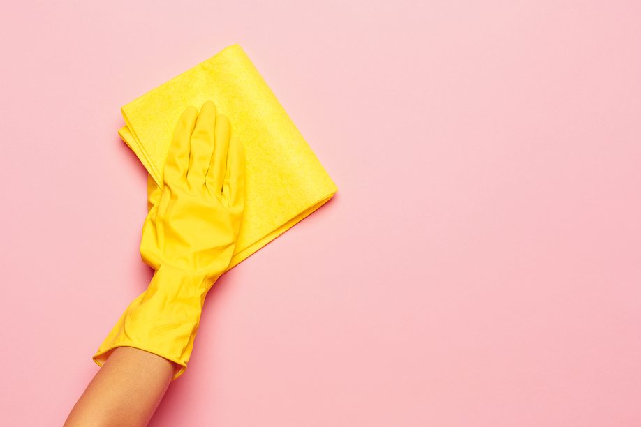 The woman's hand cleaning on a pink background. Cleaning or housekeeping concept background. Frame for text or advertising