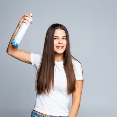Attractive woman spraying hairspray isolated on a white background