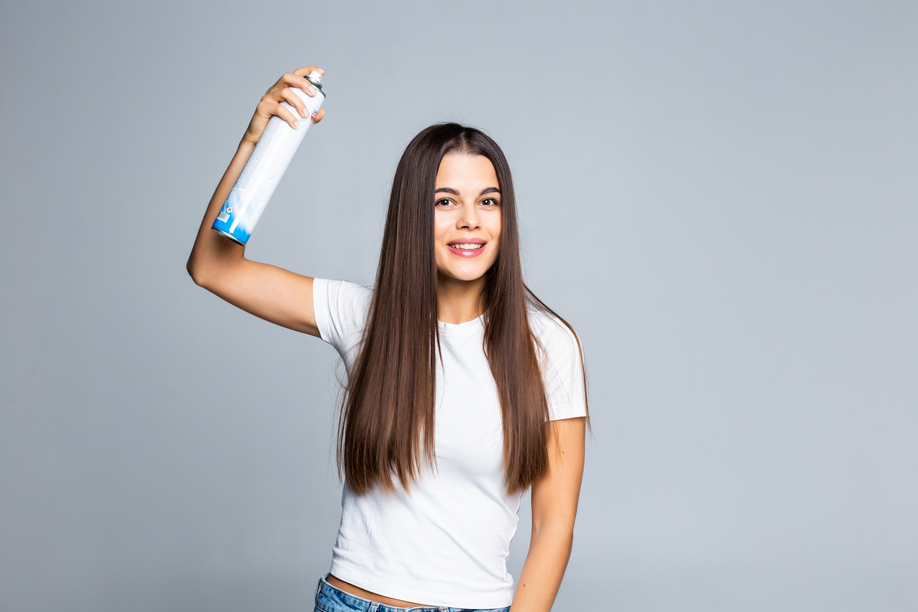 Attractive woman spraying hairspray isolated on a white background