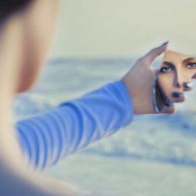 Female fair haired model in mirror looking herself
