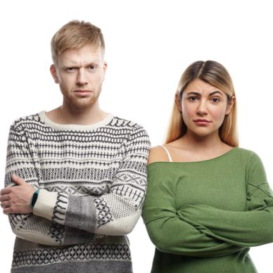 Horizontal shot of distrustful young couple crossing arms in studio and staring at camera, having doubtful skeptical looks. Human facial expressions, emotions, feelings, attitude and body language
