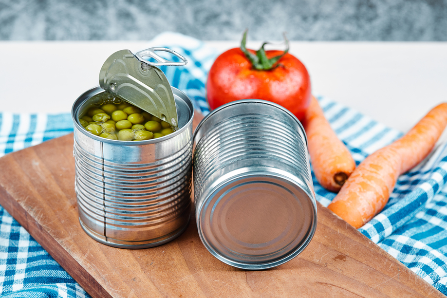Two cans of boiled green peas, vegetables and tablecloth on a white and marble background. High quality photo