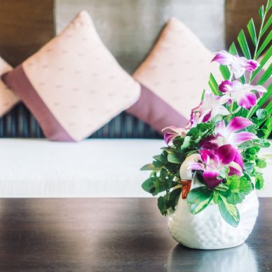 Selective focus point on vase flower decoration in living room area with pillow on sofa - Vintage light Filter