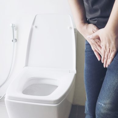 Woman holding hand near toilet bowl - health problem concept