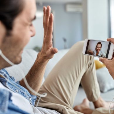 Close-up of a man using mobile phone and waving while having video chat with his girlfriend.
