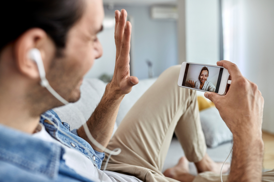 Close-up of a man using mobile phone and waving while having video chat with his girlfriend.