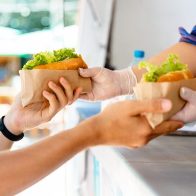 Man buying two hot dog in a kiosk, outdoors. Street food. Close-up view.