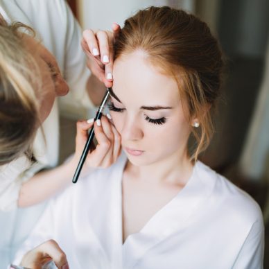 Portrait preparation of bride in the morning before wedding. Artist makes makeup and she keeps eyed closed