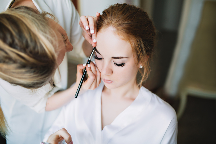 Portrait preparation of bride in the morning before wedding. Artist makes makeup and she keeps eyed closed