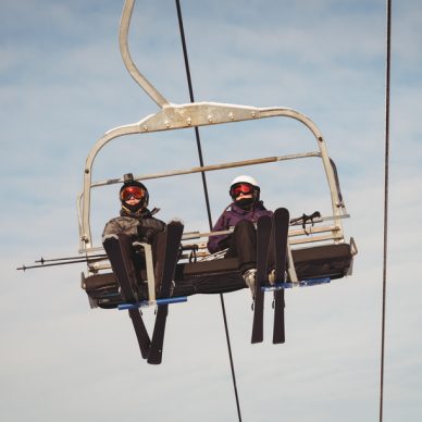 Low angle view of two skiers travelling in ski lift at ski resort