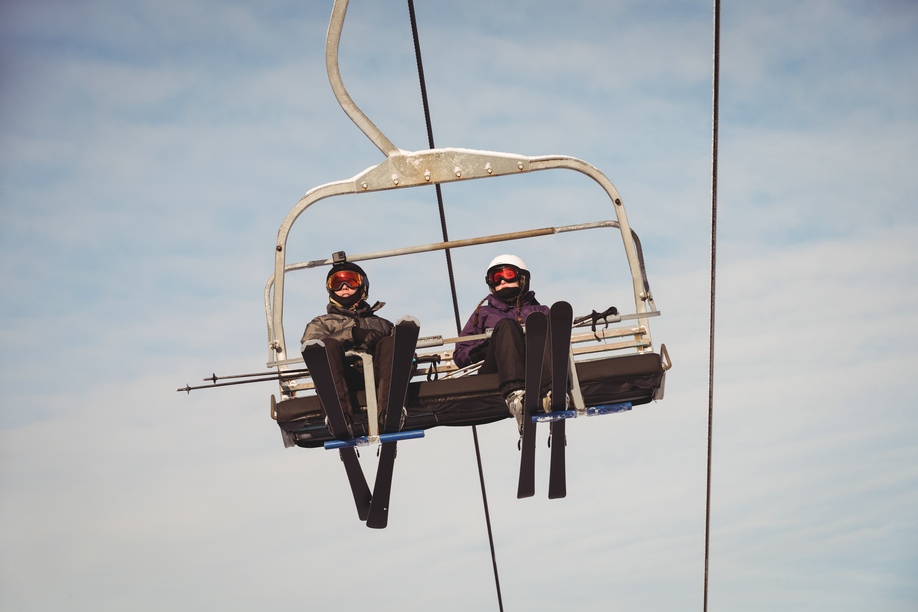 Low angle view of two skiers travelling in ski lift at ski resort