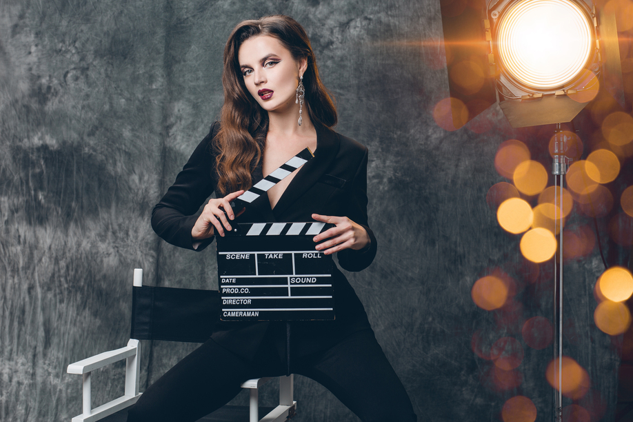 young beautiful stylish sexy woman on cinema backstage, holding movie clapper