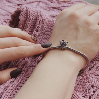 A closeup shot of a female wearing a fashionable bracelet with charm pendants