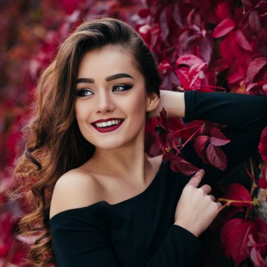 The beautiful girl stands near walll with leaves