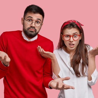 Two hesitant unshaven man and dissatisfied woman shrug shoulders, feel unsure, have doubt while make decision, stand closely to each other against pink background, look confused and questioned