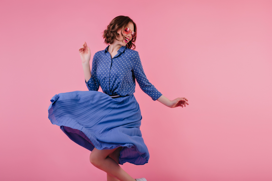Magnificent female model in midi skirt dancing and laughing on pink background. Studio portrait of excited caucasian woman in blue clothes expressing positive emotions.