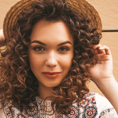 Closeup beautiful model with afro curls hairstyle dressed in summer hipster white dress.Sexy carefree girl posing in the street near yellow wall.Beauty concept