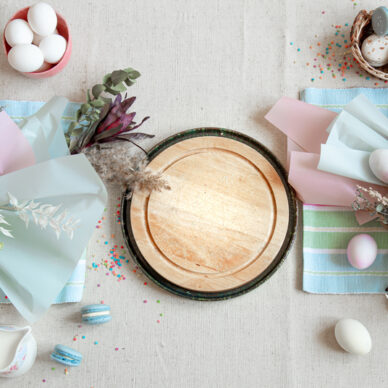 Easter composition with flowers, eggs and wooden space for text in pastel colors flat lay.