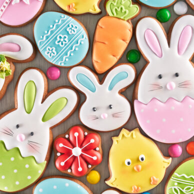 From above view of colorful ginger glazed cookies and chocolate balls isolated on wooden background. Close up of homemade lovely delicious pastry in shape of easter animals, eggs, flowers and carrots.