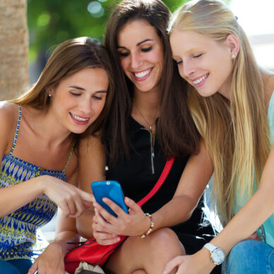 Outdoor portrait of group of friends having fun with smartphones.