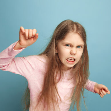 The hate, rage. The screaming surprised teen girl on a blue studio background. Facial expressions and people emotions concept. Trendy colors. Front view. Half-length portrait