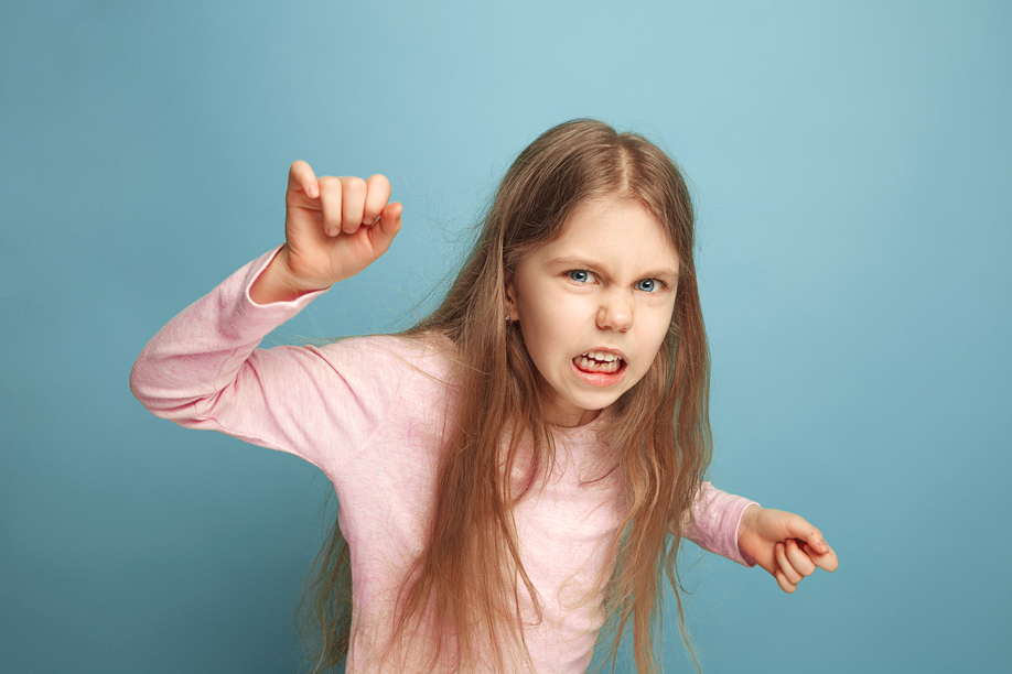 The hate, rage. The screaming surprised teen girl on a blue studio background. Facial expressions and people emotions concept. Trendy colors. Front view. Half-length portrait