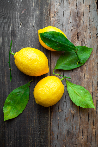 Lemons with leaves on dark wooden background, top view. vertical