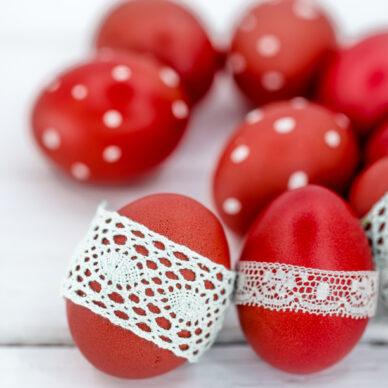 Red Easter eggs on white background tied lace tape , close-up , lying on a white wooden background still life