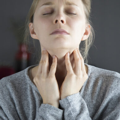 Sick young fair-haired Caucasian woman with closed eyes having sore throat, touching her neck. Illness, pain concept