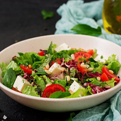 Dietary salad with tomatoes, feta, lettuce, spinach and pine nuts.