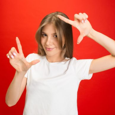 Framing, sefie. Portrait of young caucasian woman isolated on red studio background with copyspace. Blonde female model. Concept of human emotions, facial expression, sales, advertising, youth.