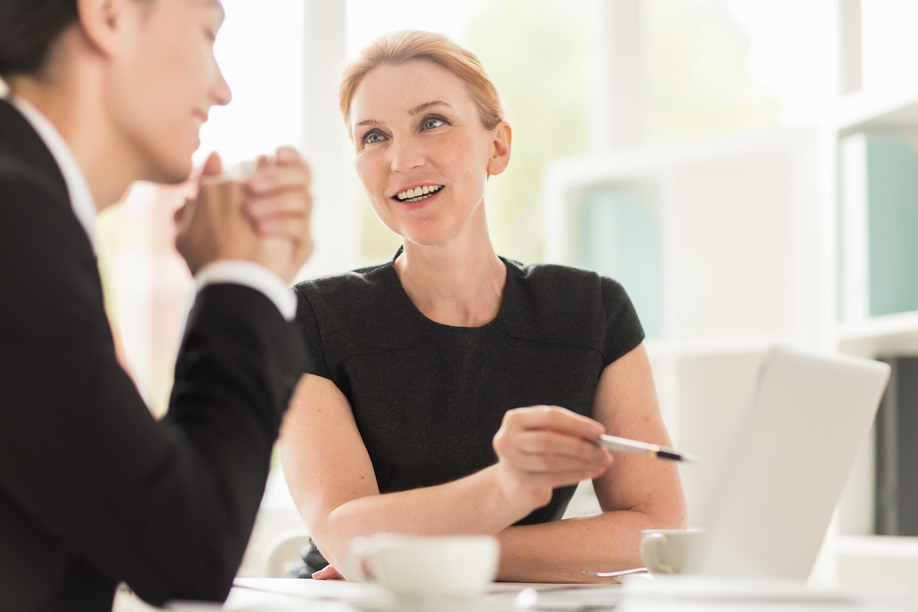 Multi-ethnic group of managers gathered together in boardroom and brainstorming on joint project, blurred background