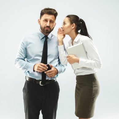 Secret, gossip concept. Young woman whispering a secret behind her hand to boss. Business woman isolated on white studio background. Young emotional woman. Human emotions, facial expression concept.