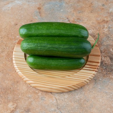 A wooden plate with fresh cucumbers on marble background. High quality photo