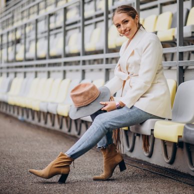 Young woman in white jacket holding hat
